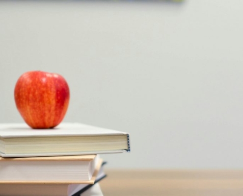 two books with an apple on top and two cubes with letter A and B