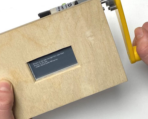 person winding a handle on a wooden box